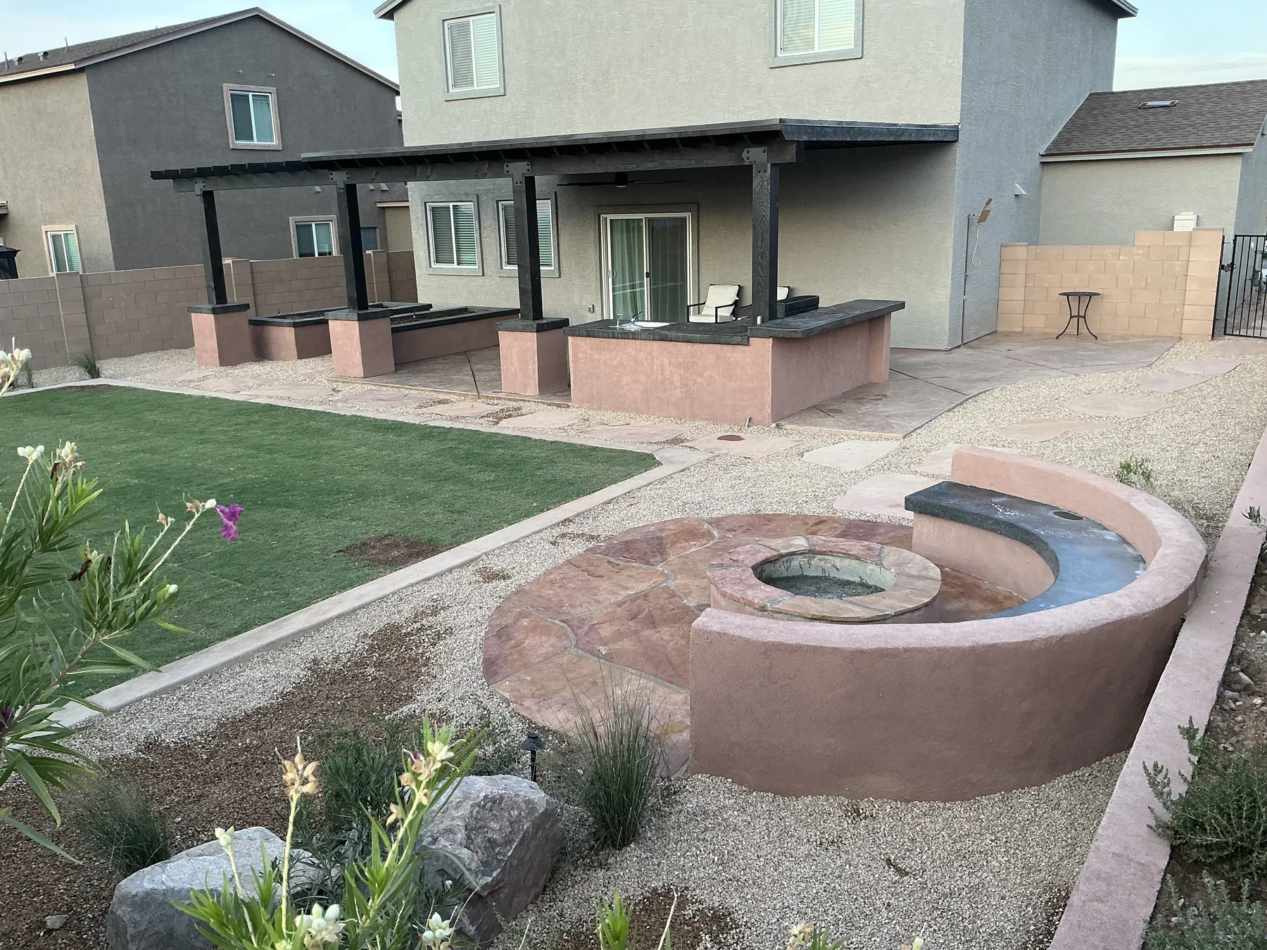 Curved paver patio with a circular fire feature in a finished backyard