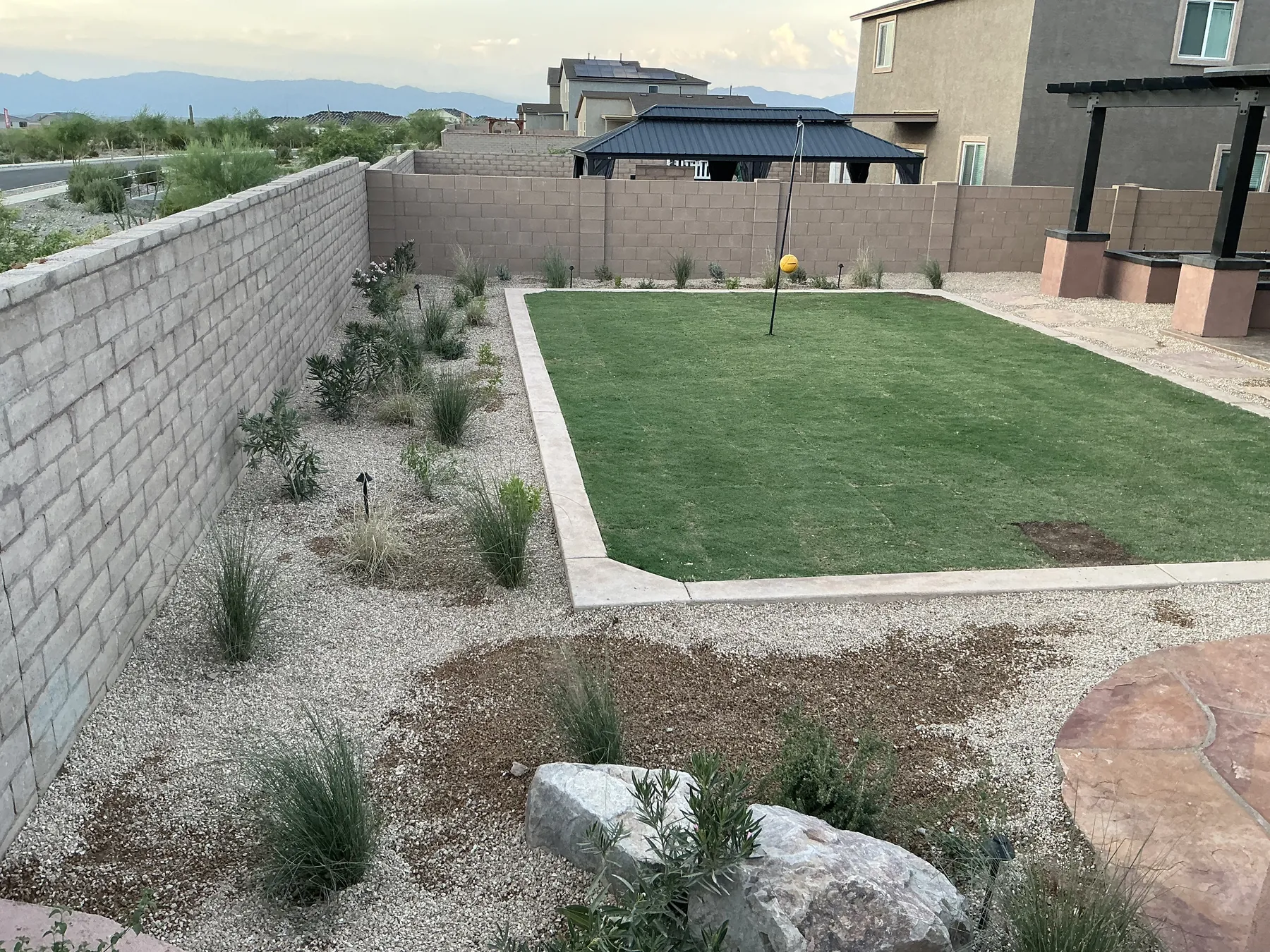 Artificial turf beside a masonry retaining wall and gravel landscape bed