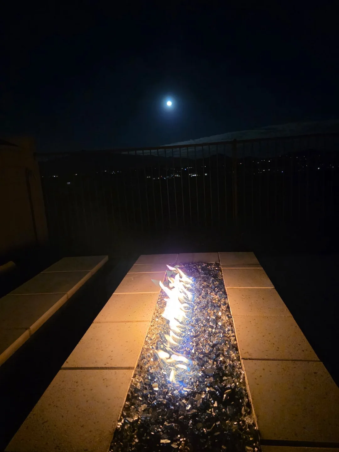 Client project with a linear fire feature set into a paver patio at night